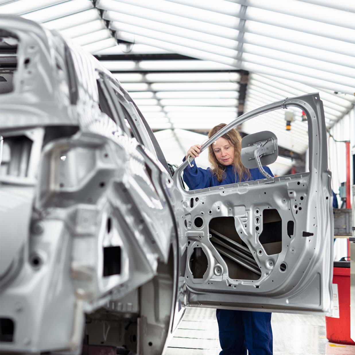 Female line worker verifying a car door installation